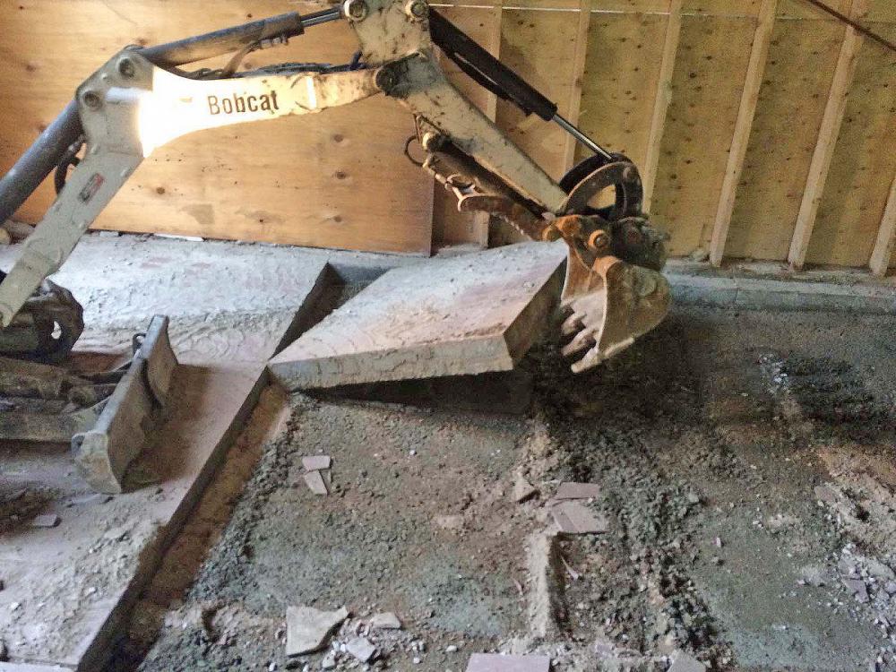 Retrait de dalle de béton avec pelle mécanique dans un bâtiment résidentiel à Montréal